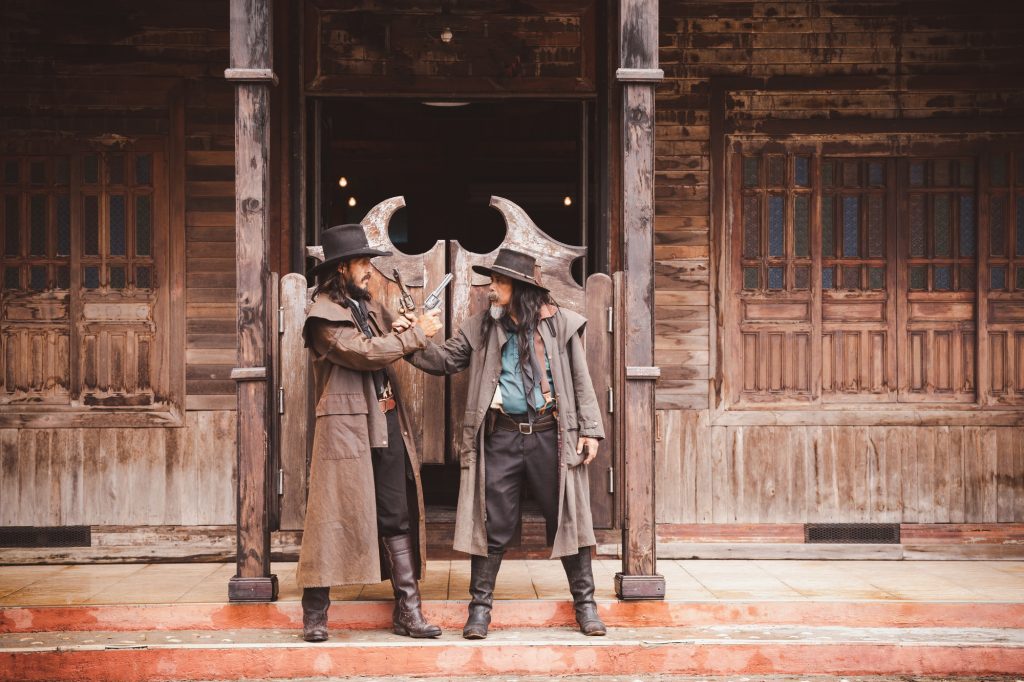 Cowboy posing shooting rifle by gun on hand to show protected weapon wearing cowboy dresser and hat